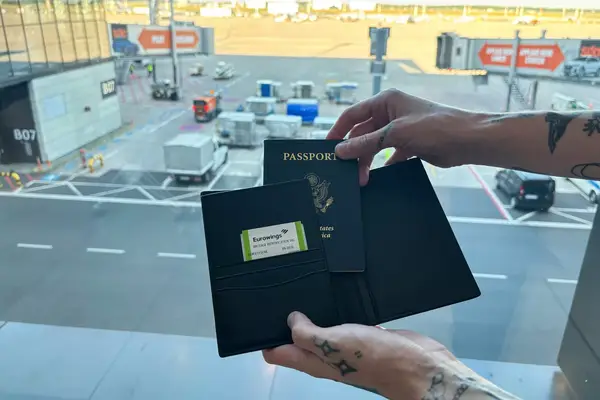 A person places a passport into the Quince Nappa Leather RFID Blocking Passport Holder