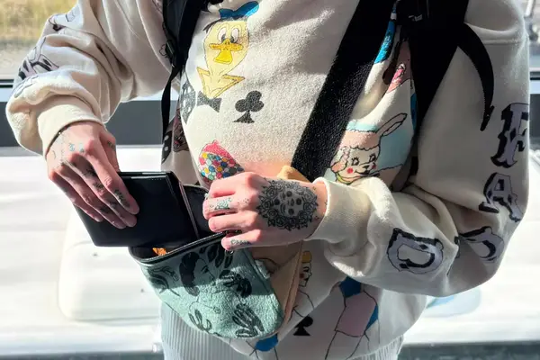 A person places the Quince Nappa Leather RFID Blocking Passport Holder into a travel bag