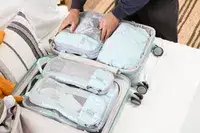 A hand packing the bagsmart compression packing cubes in a suitcase