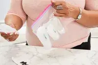 Person holding ziplock bag with Liquisnugs Premium Leak-Proof Silicone Travel Bottles