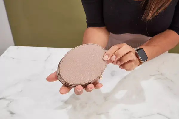 Hands holding a closed Cuyana Travel Jewelry Case