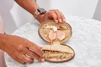 Hands holding an opened Cuyana Travel Jewelry Case