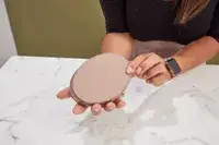 Hands holding a closed Cuyana Travel Jewelry Case