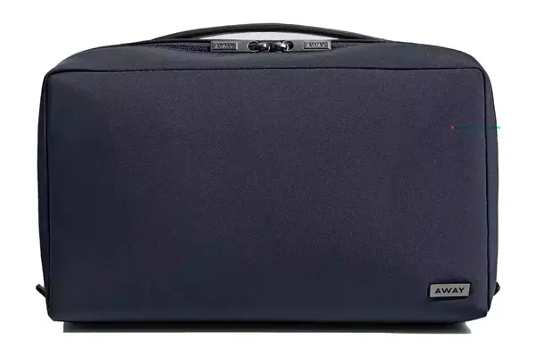 A person holding the Ostrich Pillow Go Neck Pillow in its travel pouch