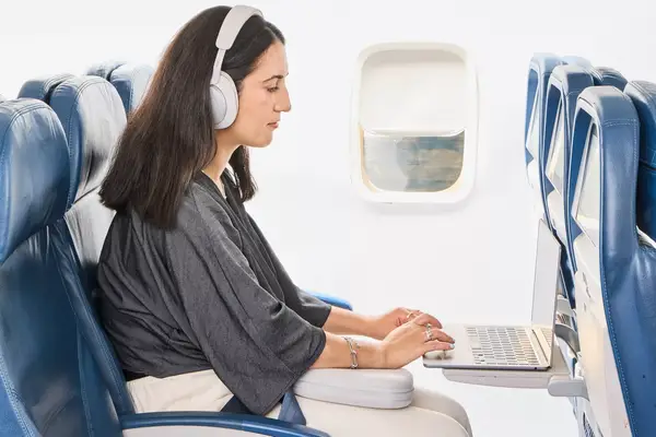 A person using a laptop on a plane while wearing the Bowers & Wilkins Px7 S2e 