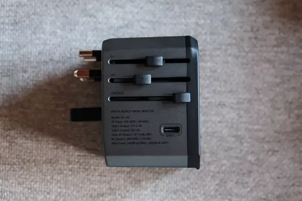 The side view of the EPICKA Universal Travel Adapter on a gray fabric background