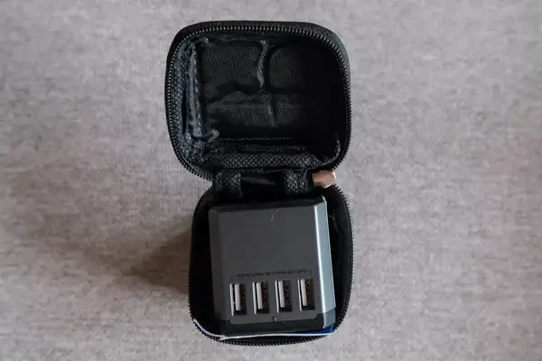 The EPICKA Universal Travel Adapter inside of its travel case on gray fabric