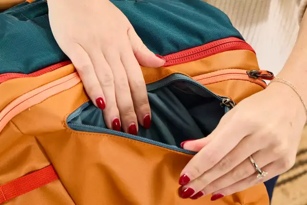 A person opens the pocket on the Cotopaxi Allpa 42L Travel Pack