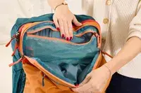 A person opens the pocket on the Cotopaxi Allpa 42L Travel Pack