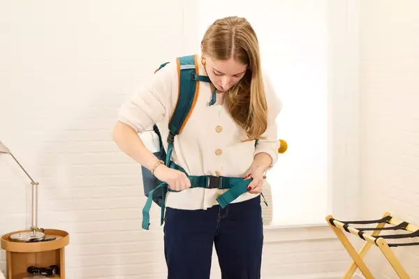 A person adjusts the waist strap on the Cotopaxi Allpa 42L Travel Pack
