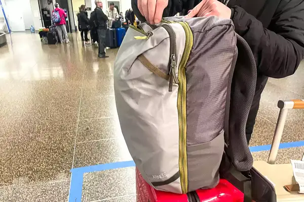 A person zips a Cotopaxi Allpa 42L Travel Pack