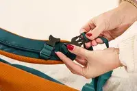 A person secures a strap on the Cotopaxi Allpa 42L Travel Pack