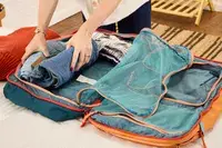 A person packs clothing into the Cotopaxi Allpa 42L Travel Pack