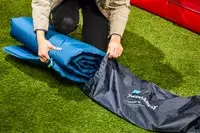 A person places the folded Therm-a-Rest BaseCamp Sleeping Pad into its carrying bag