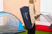 A person carries the Therm-a-Rest BaseCamp Sleeping Pad in its carrying case on their shoulder