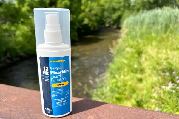 A bottle of Sawyer Picaridin Insect Repellent on a railing outside