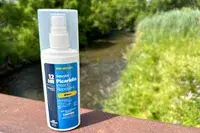 A bottle of Sawyer Picaridin Insect Repellent on a railing outside