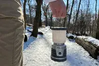 a person holding Ultimate Survival Technologies 30-Day Duro Lantern outside