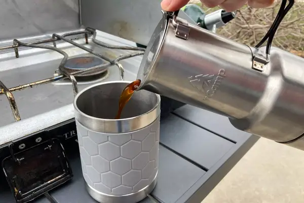 A person pours coffee from the nCamp CafÃ© Portable Coffee Maker into a mug