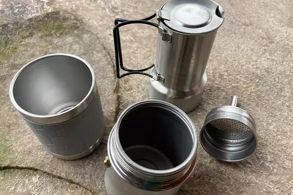 The parts of the nCamp CafÃ© Portable Coffee Maker on a rock