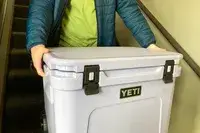 A person carrying Yeti Roadie 60 Wheeled Cooler
