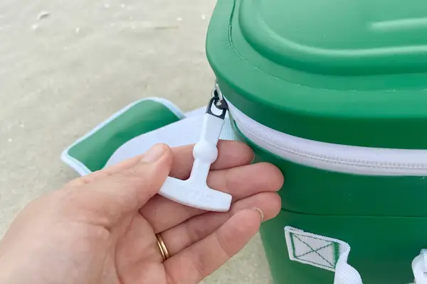 A hand holding the zipper of the RTIC Insulated Soft Cooler Bag