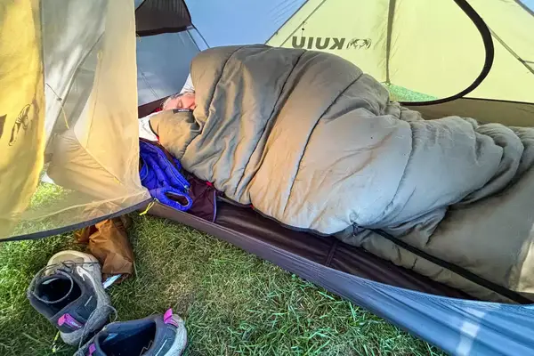 A person sleeps in a sleeping bag inside the Kuiu Mountain Star 2 Person Tent