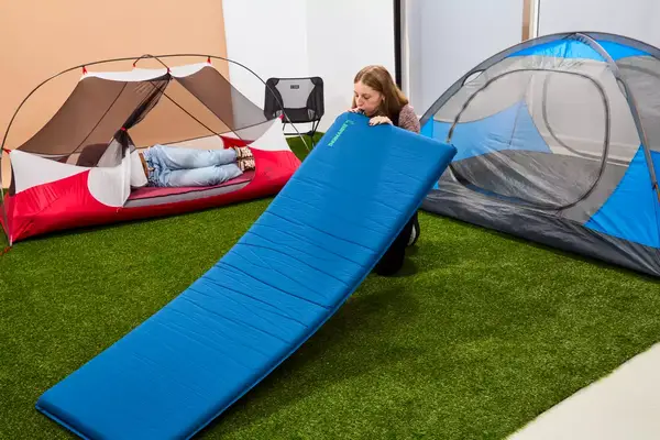 A person inflates the Therm-a-Rest BaseCamp Sleeping Pad by mouth