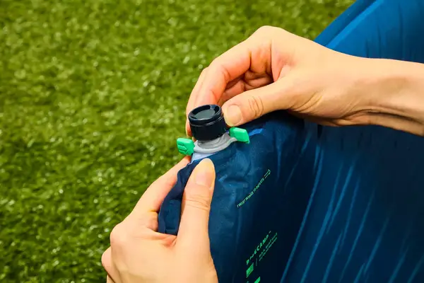 Hands removing the cap on the inflation valve on the Therm-a-Rest BaseCamp Sleeping Pad