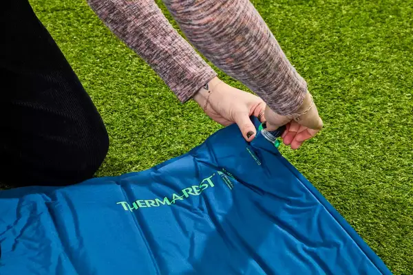 Hands placing a cap on the inflation valve on the Therm-a-Rest BaseCamp Sleeping Pad