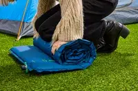 A person rolls up the Therm-a-Rest BaseCamp Sleeping Pad