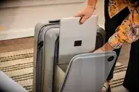 A person places a laptop into the Monos Expandable Carry-on Pro