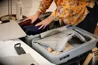 A person packs the Monos Expandable Carry-on Pro