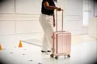 A person wheels the Calpak Ambeur Carry-On across the floor