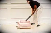 A person hits the Calpak Ambeur Carry-On with a baseball bat