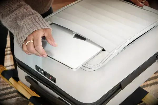 A person places a laptop into the front pocket of the Away The Front Pocket Bigger Carry-On