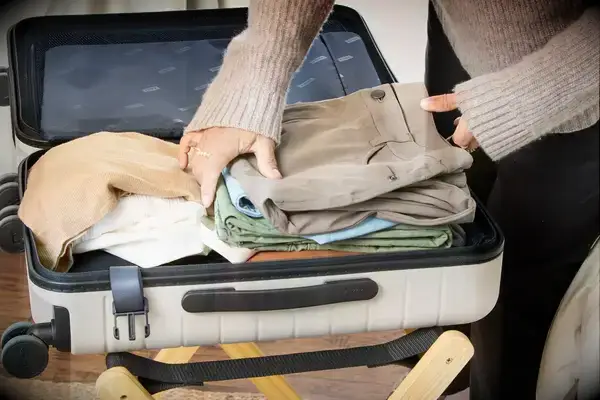A person packs clothing into the Away The Front Pocket Bigger Carry-On