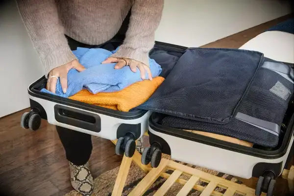 A person packs clothing into the Away The Front Pocket Bigger Carry-On