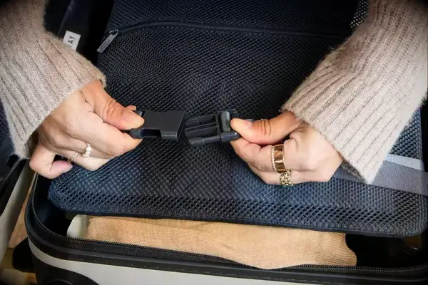 A person secures the strap on the Away The Front Pocket Bigger Carry-On