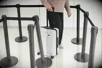 A person rolls the Away The Front Pocket Bigger Carry-On through an airport line