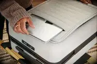 A person places a laptop into the front pocket of the Away The Front Pocket Bigger Carry-On