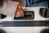 A person carries the Away The Front Pocket Bigger Carry-On by the top handle