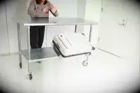 A person throws the Away The Front Pocket Bigger Carry-On off of a rolling cart
