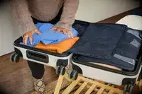 A person packs clothing into the Away The Front Pocket Bigger Carry-On
