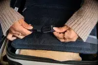 A person secures the strap on the Away The Front Pocket Bigger Carry-On