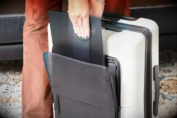 A person places a laptop into the side pocket of a July Carry On Pro SnapSleeve