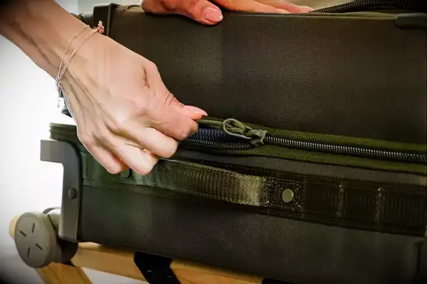 A person zippering the Dagne Doverr Seattle Carry On Rolling Luggage 20.5