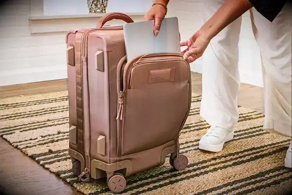 A person places a laptop into the front pocket of the Dagne Dover Smaller Seattle Carry-on Luggage 20.5 Inches