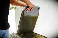 A person placing a laptop inside of a compartment in the Dagne Doverr Seattle Carry On Rolling Luggage 20.5