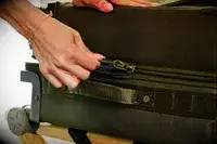 A person zippering the Dagne Doverr Seattle Carry On Rolling Luggage 20.5